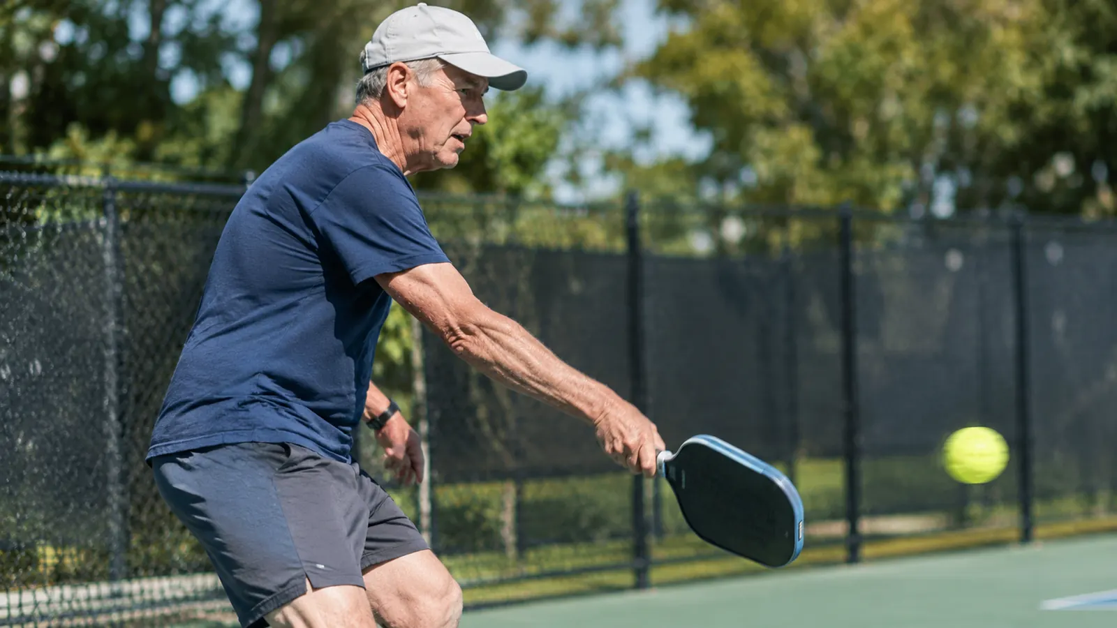 A man in his sixties playing pickleball outdoors on a sunny morning
