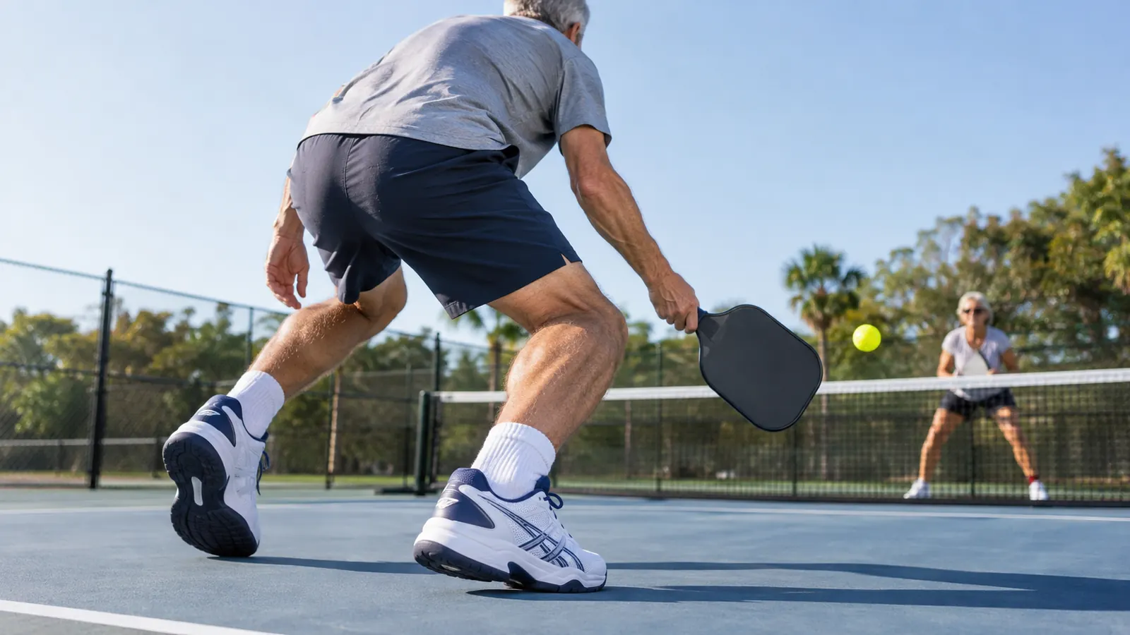 A close view of a man's feet in court shoes as he steps to the kitchen line on an outdoor pickleball court