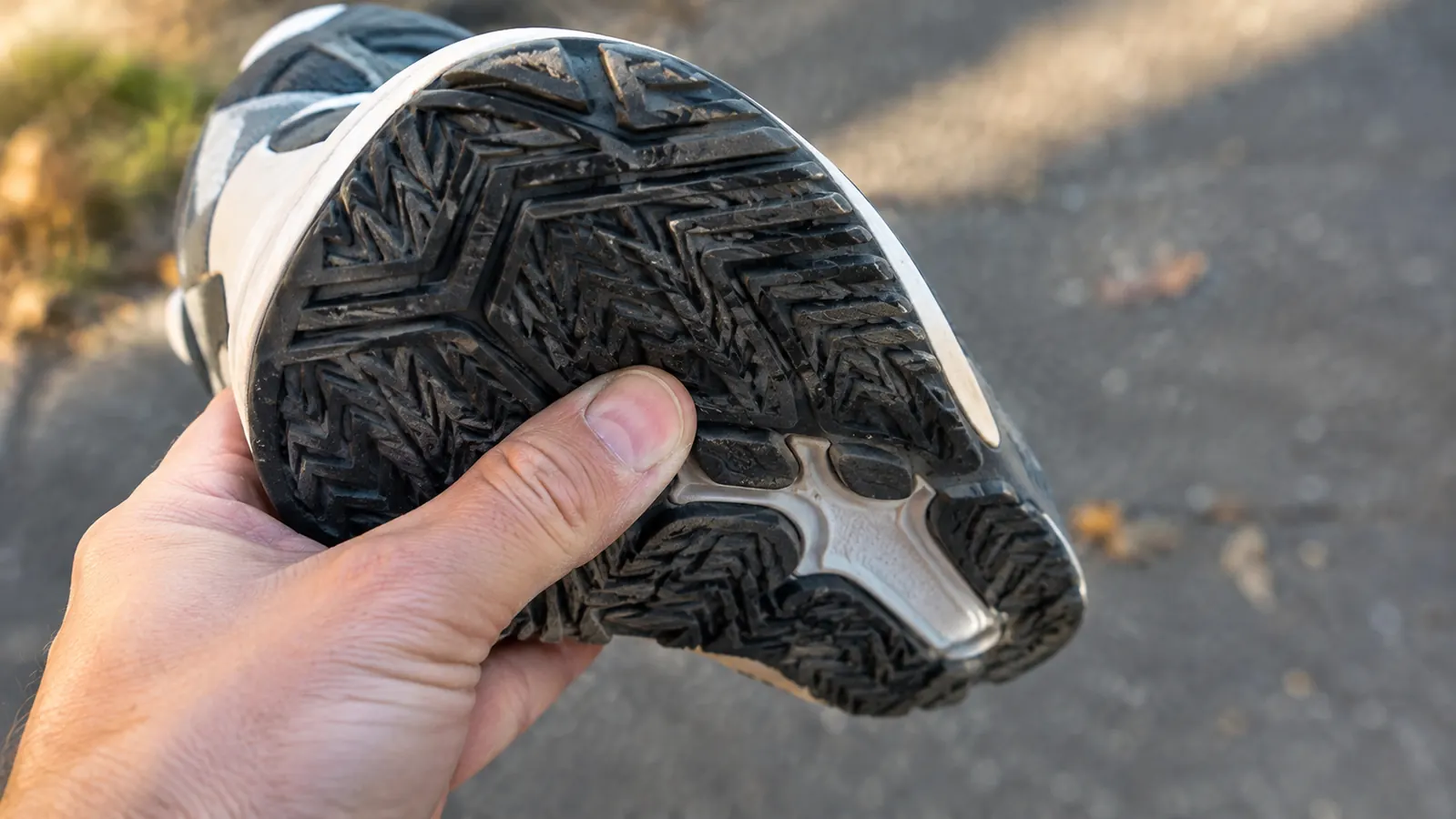 A close-up of a hand rubbing a thumb along the outsole of a court shoe to check wear